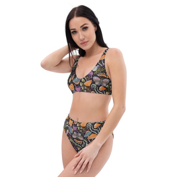 A model wearing a high-waisted bikini set made from recycled materials with a whimsical mushroom design. The top has a scoop sport bra style, and the bottom has a flattering high-waist cut.